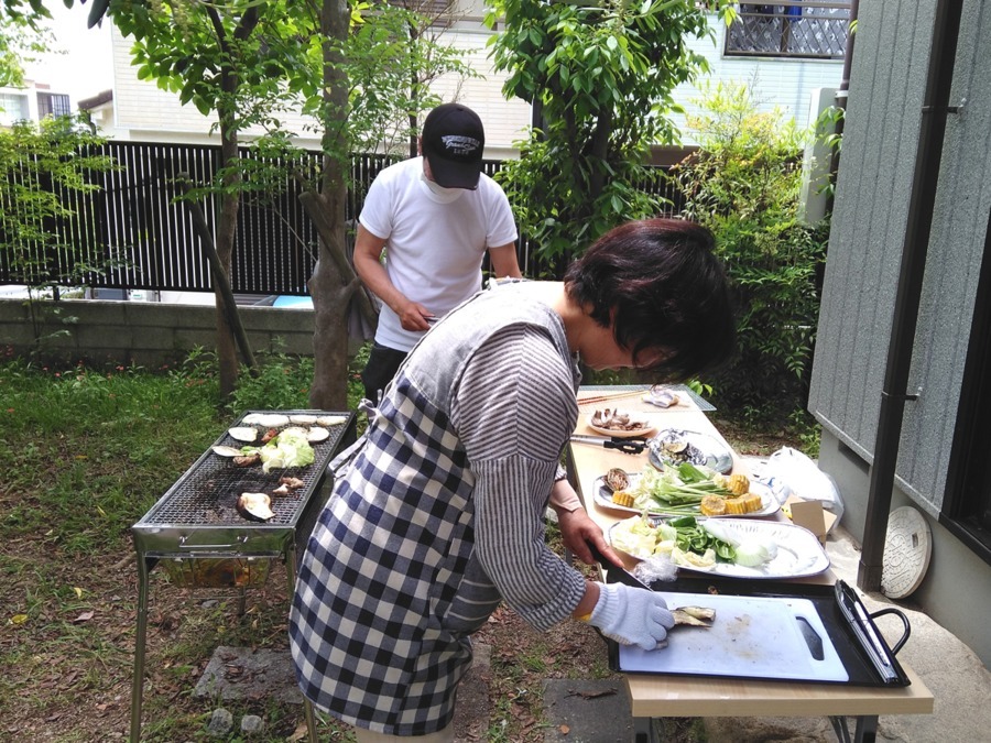 庭でのバーベキュー。スタッフと利用者が一緒に食材を焼く様子
